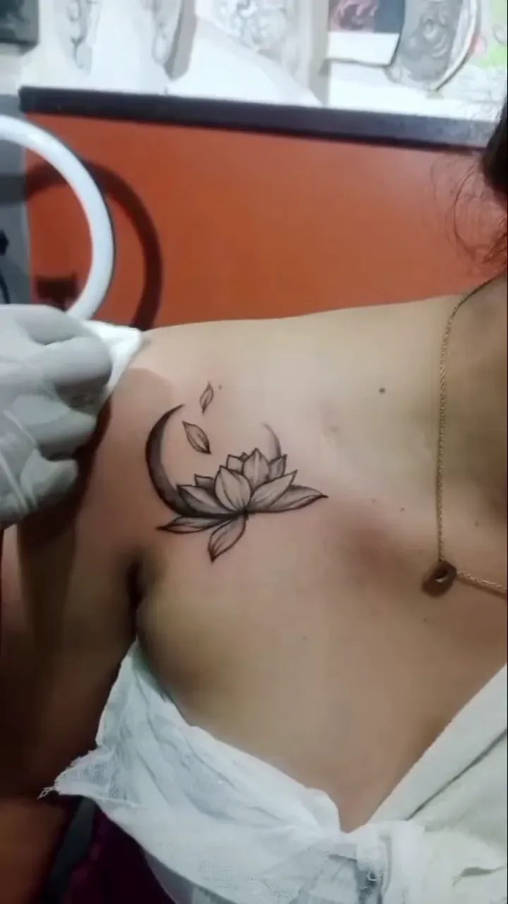 Fine line lotus tattoo on the upper back near the shoulder