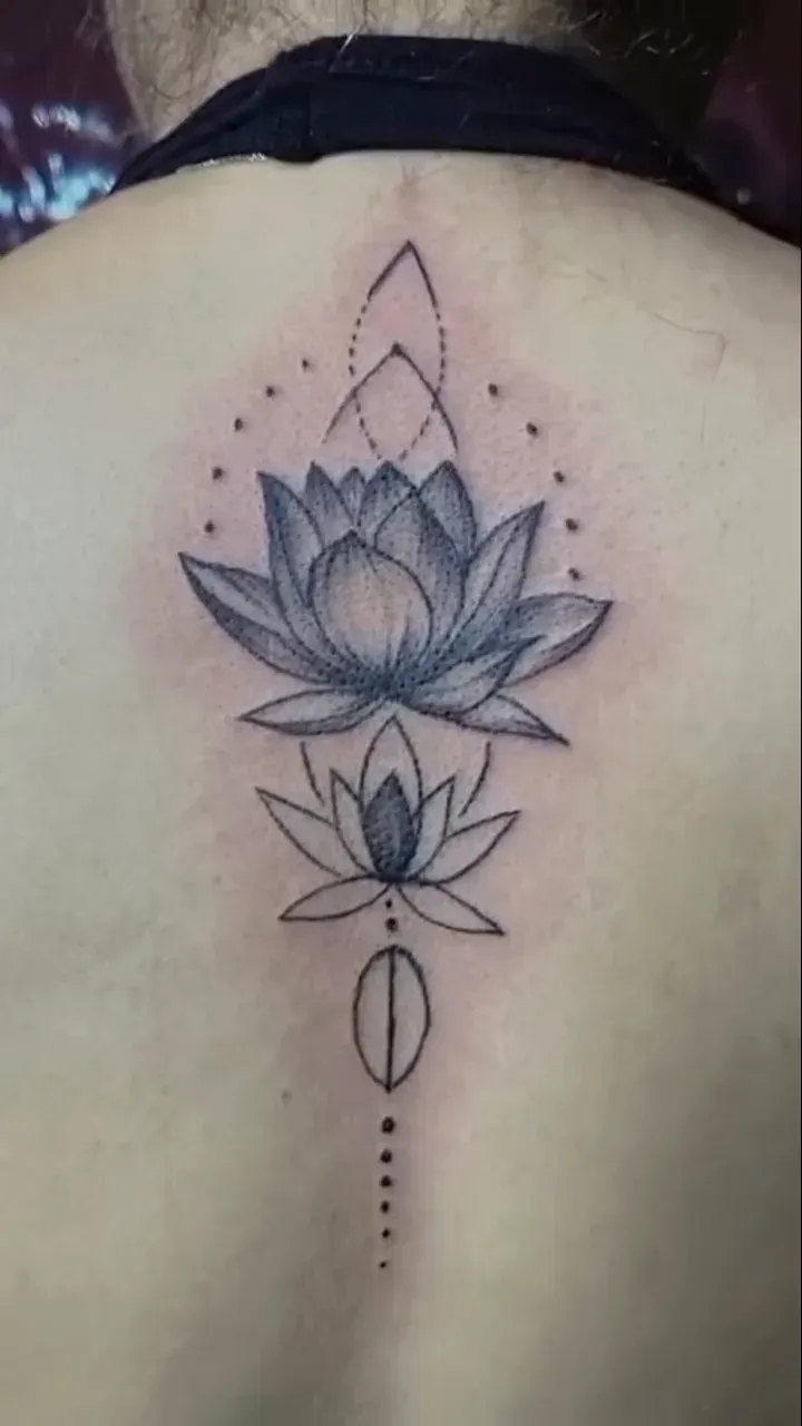 Ornamental fine line lotus with dotwork accents along the upper spine